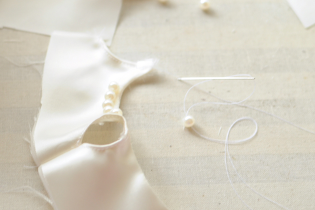 Attaching white pearls to teddy bear dress